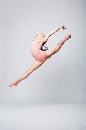 Portrait of a young ballet dancer suspended in the air in a leap.