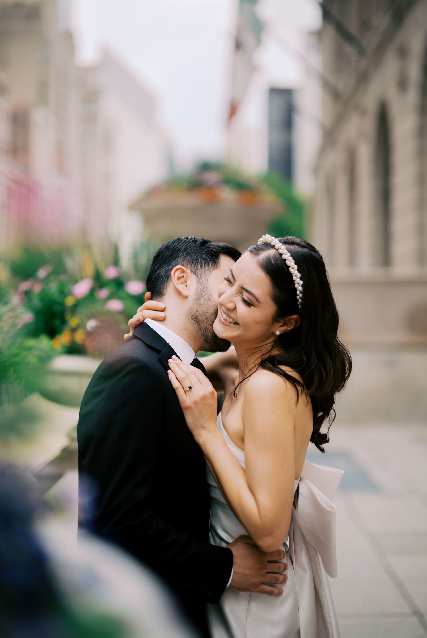 A couple embraces and laughs together during their romantic photoshoot on a city street.