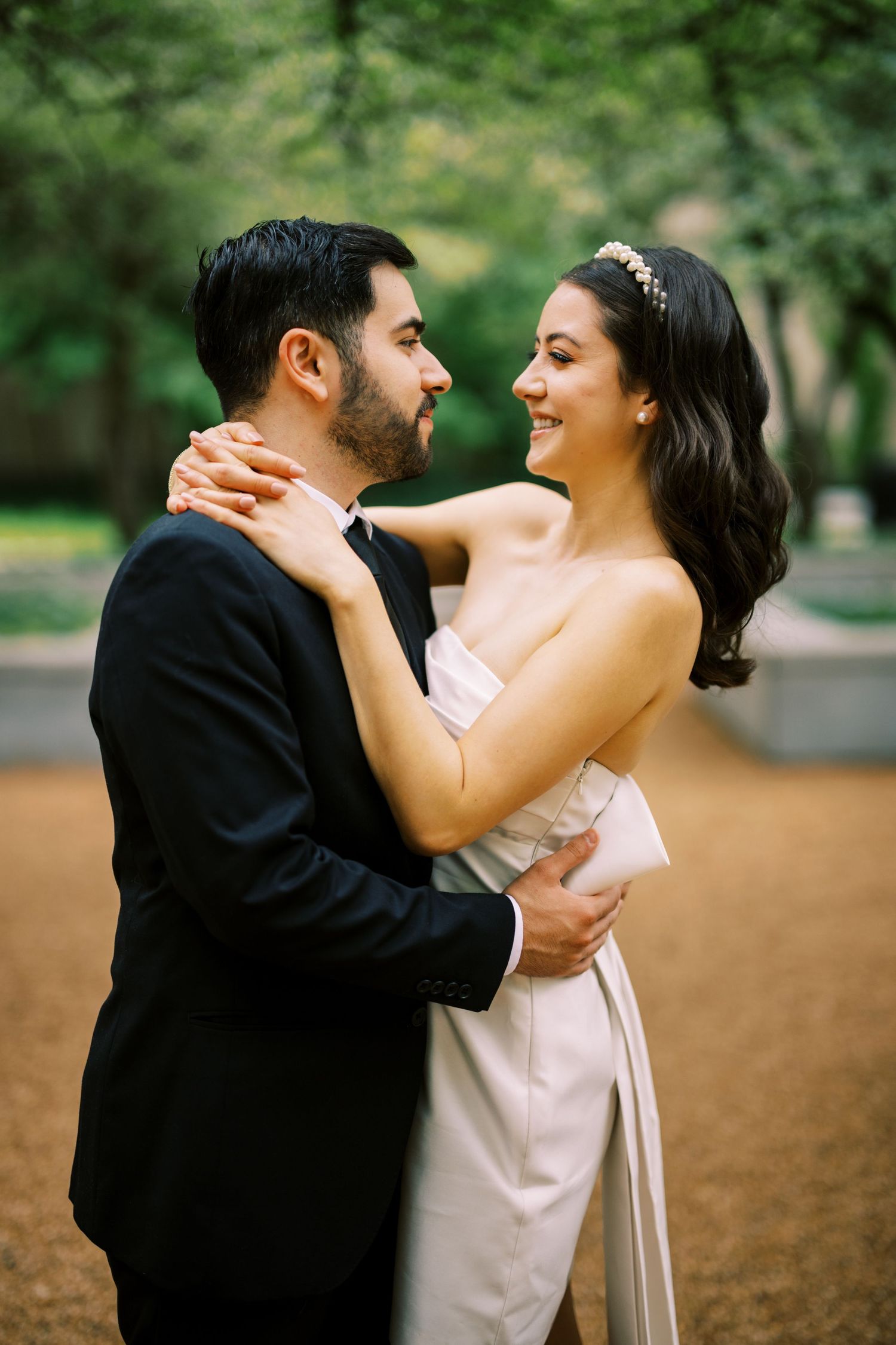 A tender moment between a couple in formal wear embracing in a garden setting.