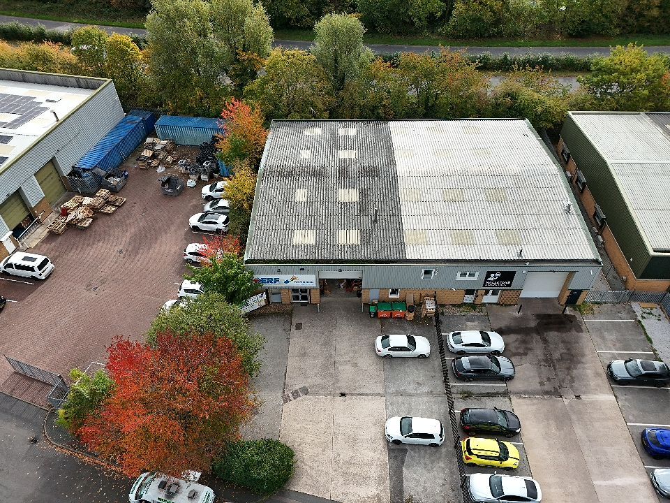 Aerial view of commercial warehouse buildings with white roofs and parking lots in an industrial area.
