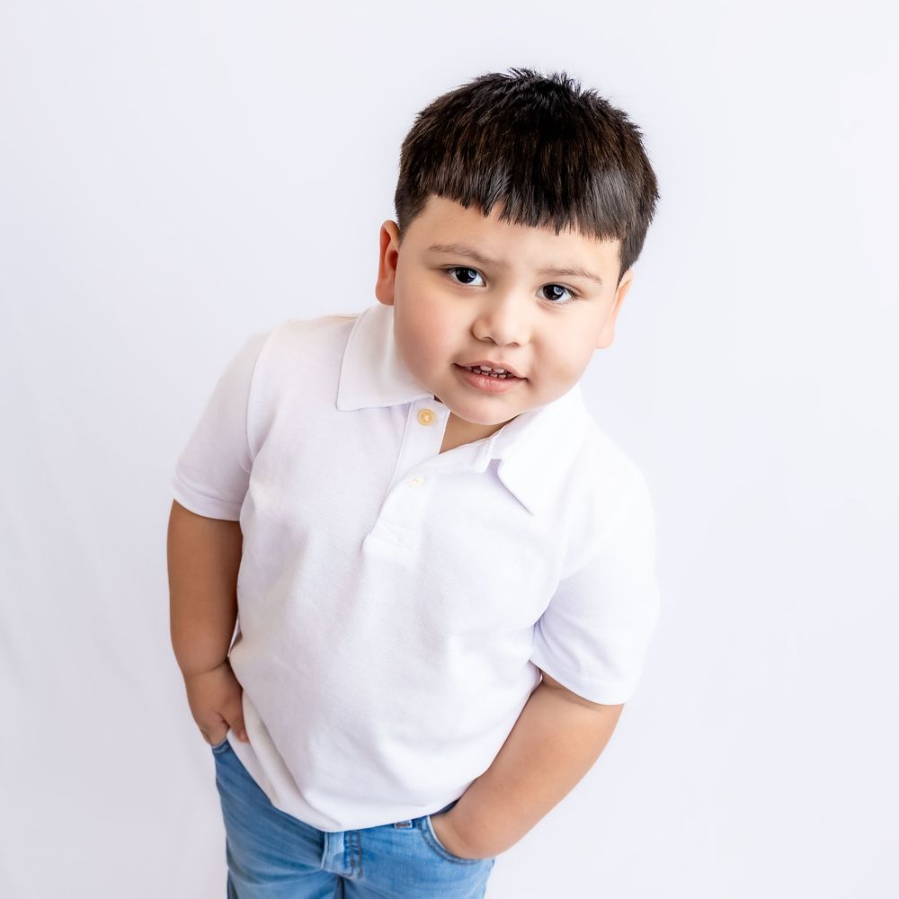 Young boy in white polo shirt and jeans posing confidently against a white background in Connell, Wa.