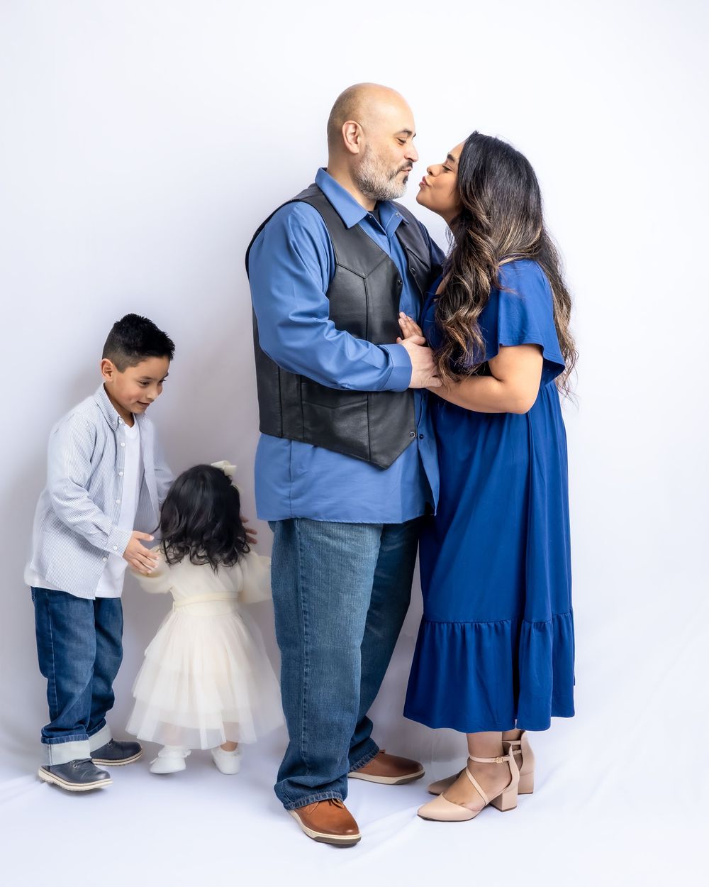 Couple sharing a tender moment while two young children play beside them in a studio setting in Connell, Wa.