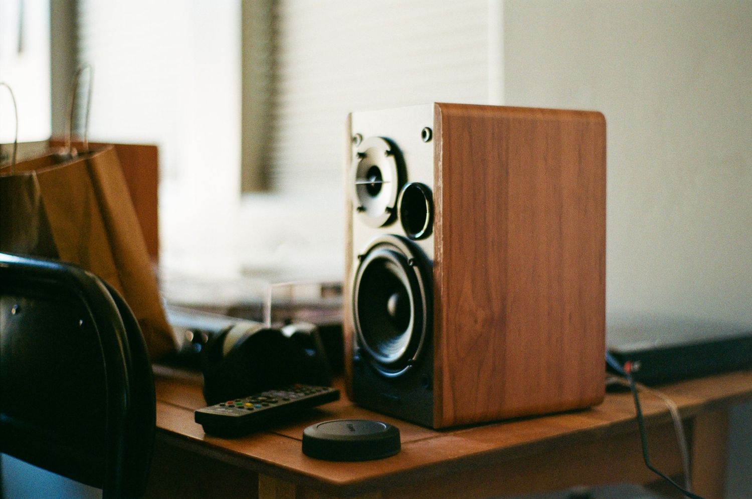Wooden bookshelf speakers with black drivers displayed in a row against a light-colored wall.