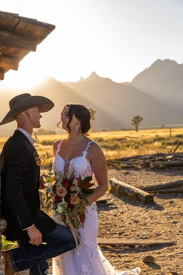 A couple shares a romantic moment at sunset in a desert landscape with mountains in the background.