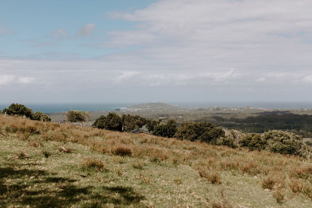 Rolling coastal hills with ocean views under cloudy skies.