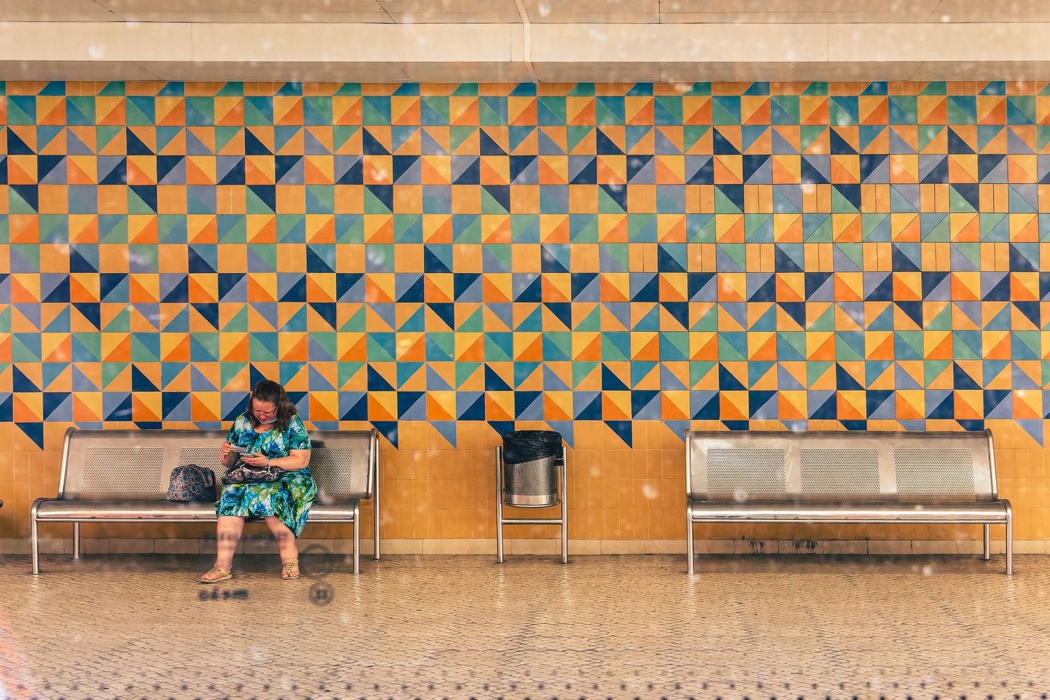Geometric pattern wall with repeating orange and teal triangular shapes and benches below.