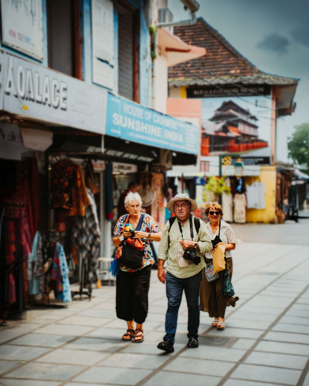 Group of people walking and browsing shops along a historic cobblestone street in a tourist town.