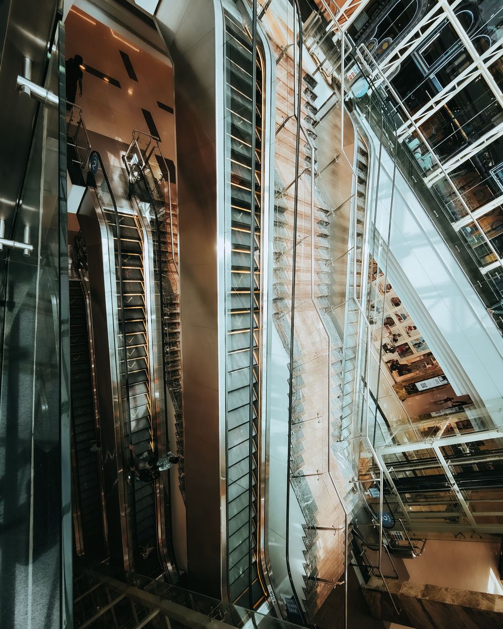Modern architectural interior with angled glass walls and metal framework creating dramatic geometric patterns and shadows.