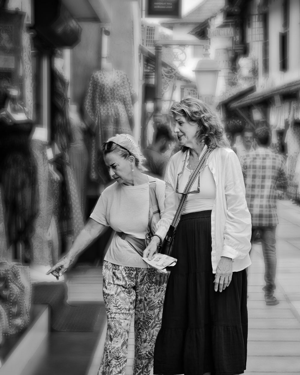 Two people in casual attire walking and conversing together on a city street.