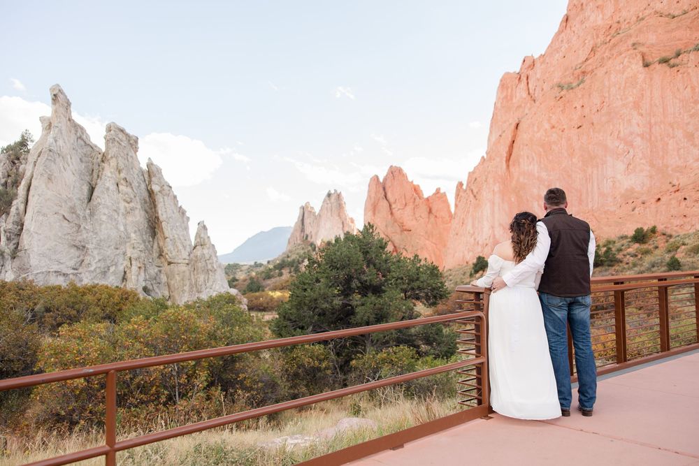 Wedding couple walks hand in hand along a scenic path at Garden of the Gods with towering rock formations.