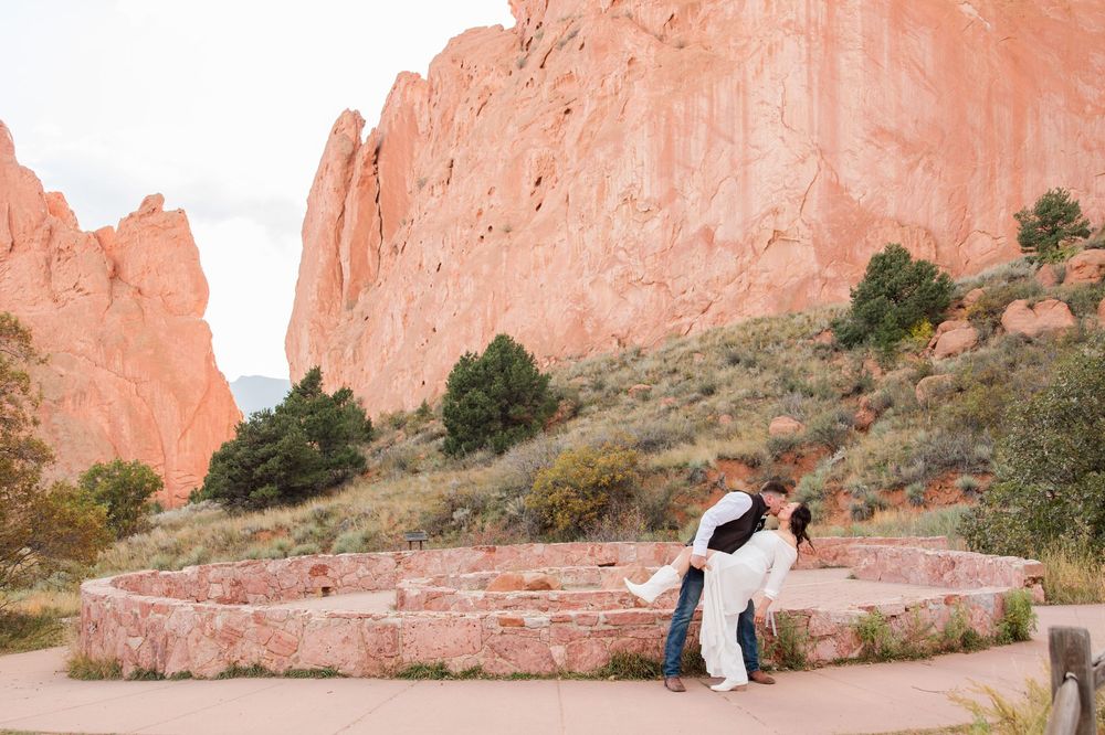 Couple embraces against stunning red rock formations at Garden of the Gods during sunset.