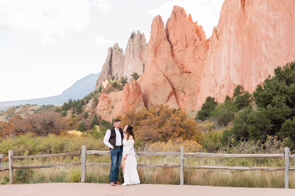 A couple stands together with the iconic red rock formations of Garden of the Gods in the background.