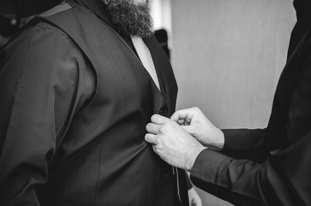 A series of black and white photos showing someone adjusting a suit jacket and tie in a formal setting.