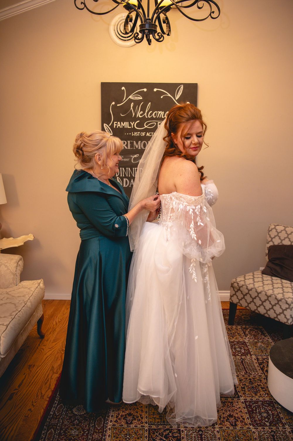 Two people share an emotional embrace in a room with a white wedding dress displayed on a mannequin.