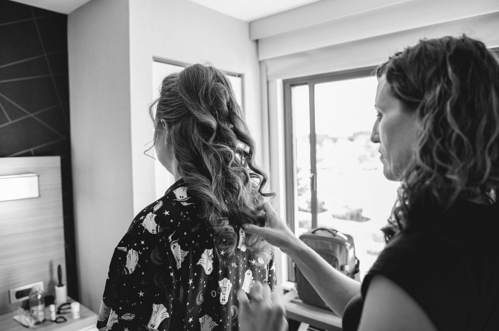 A series of black and white photographs showing someone getting their hair styled and prepared in a salon setting.