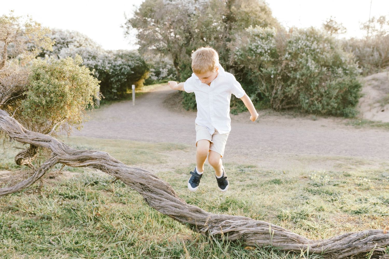 A person wearing white runs and jumps across a grassy outdoor area during sunset.
