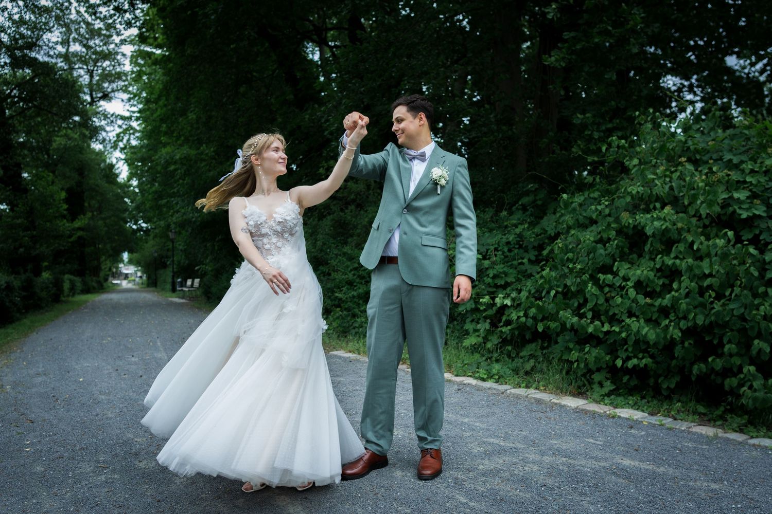 Ein Brautpaar teilt ihren ersten Tanz im Freien vor einer rustikalen Backsteinscheune an einem sonnigen Hochzeitstag.