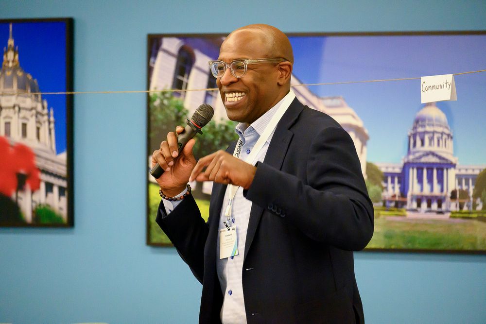 A series of five similar photos showing a speaker gesturing enthusiastically against a backdrop with architectural images.