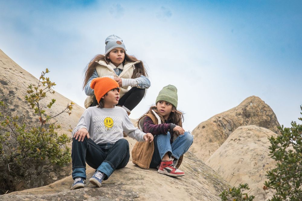 Hikers take a break while sitting on rocky terrain against a bright blue sky backdrop.