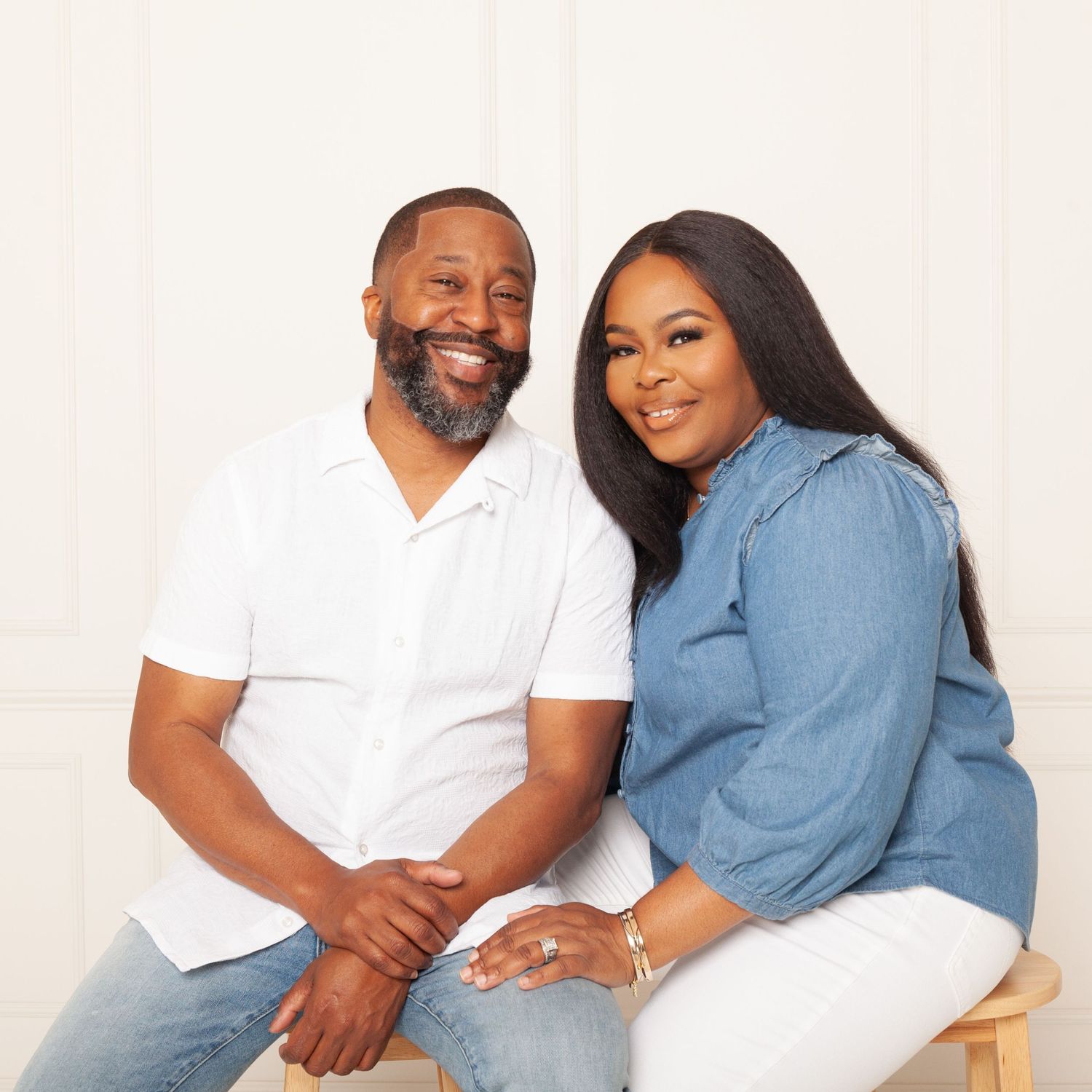 Couple sitting together in coordinated casual outfits of white and denim blue.