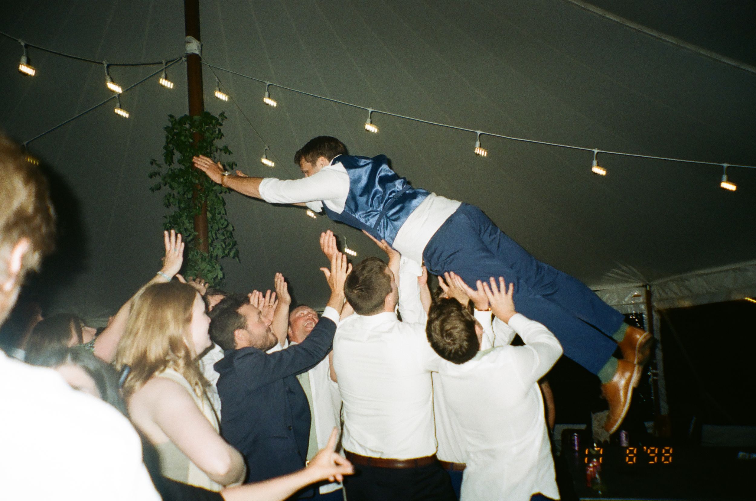 People dancing and celebrating at a lively party with confetti falling from above in a dimly lit room.