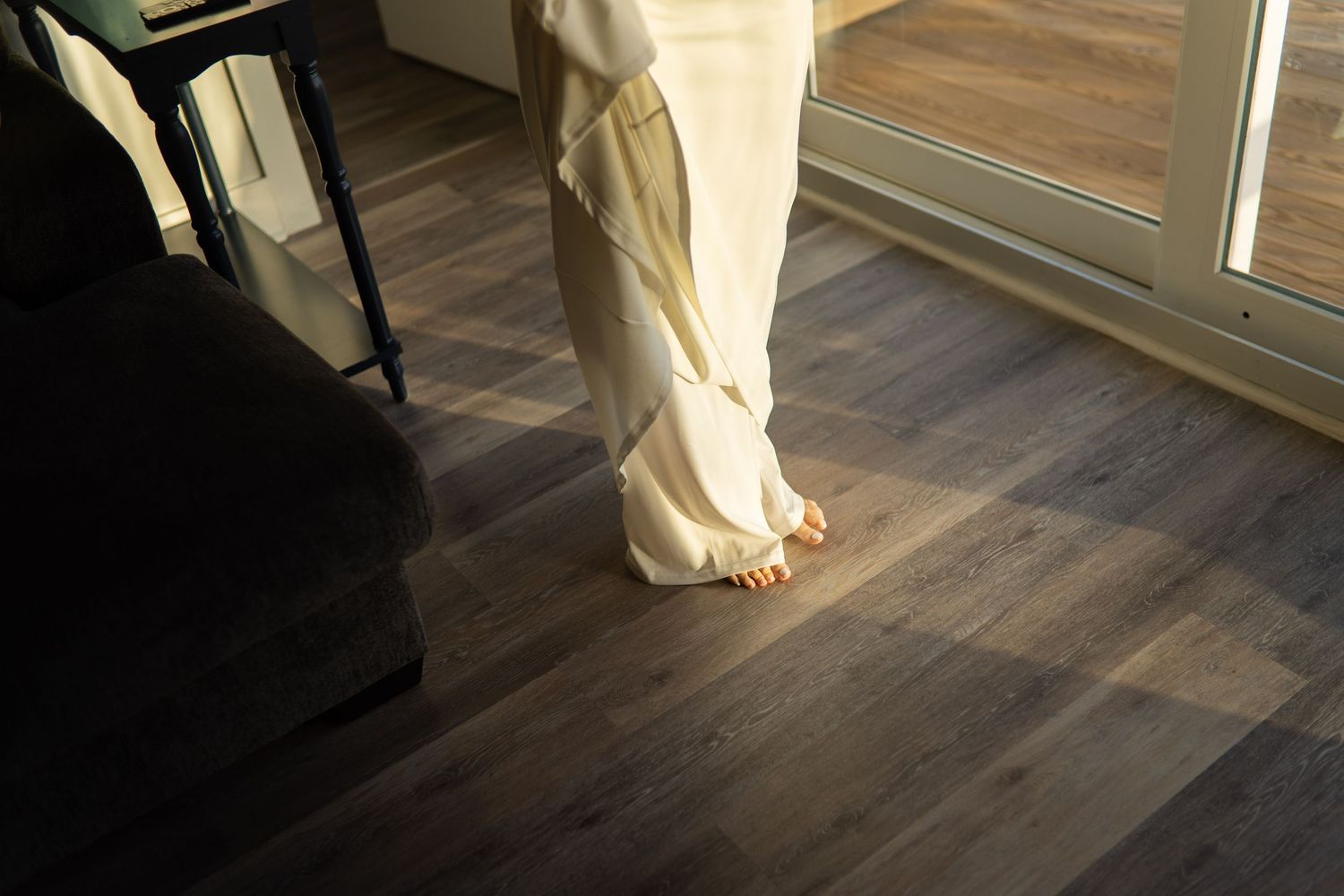 A person in a white wedding dress walks across a dark hardwood floor showing the flowing movement of the fabric.