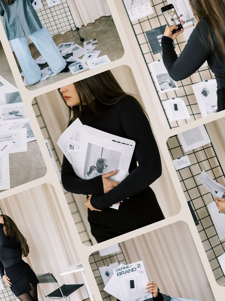 Person in black attire arranging papers on a white tiled wall display board.