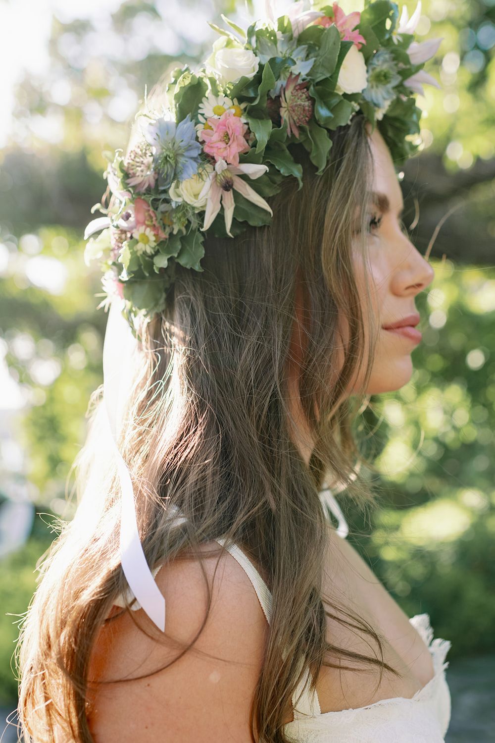 Delicate floral crown with white and pink blooms adorns a soft, natural hairstyle in outdoor lighting.