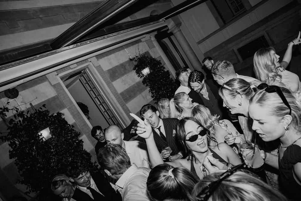 Black and white photograph showing a crowded dance floor with people dancing and socializing at a party.