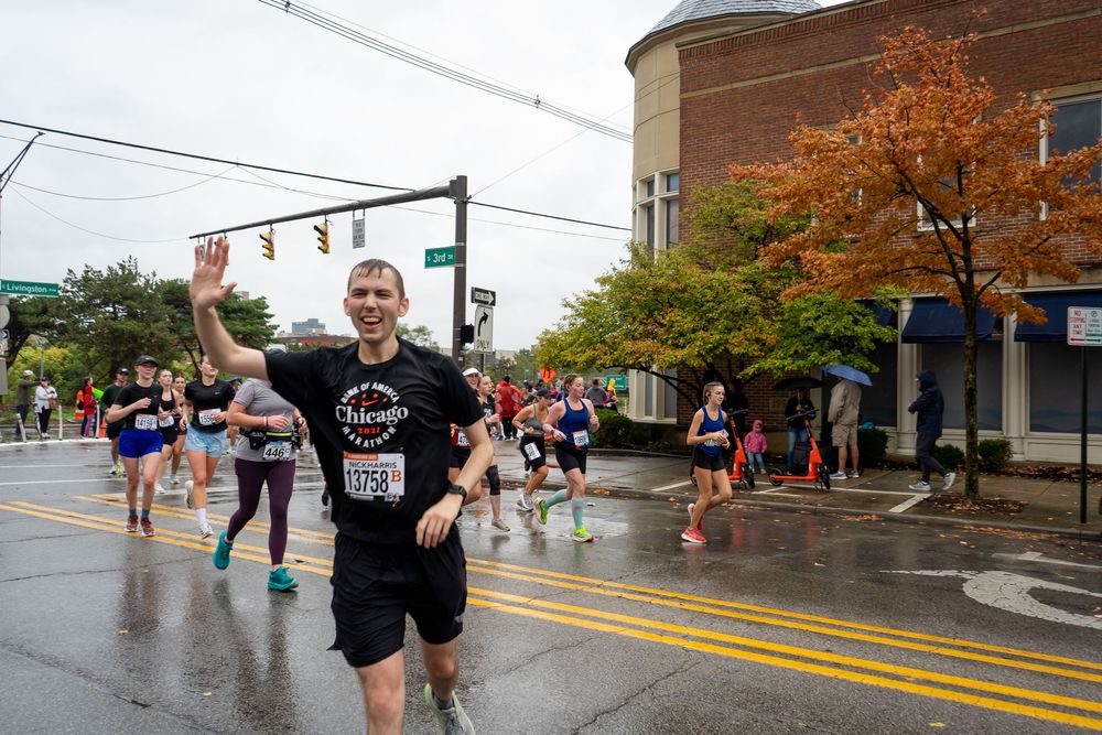 Marathon runners splash through puddles on a rainy race day as they make their way down a city street.