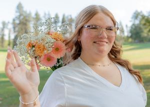 Someone holding a beautiful bouquet of peach gerbera daisies and baby's breath against an autumn backdrop.