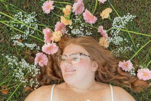 Overhead shot of someone lying on grass surrounded by pink flowers and baby's breath.