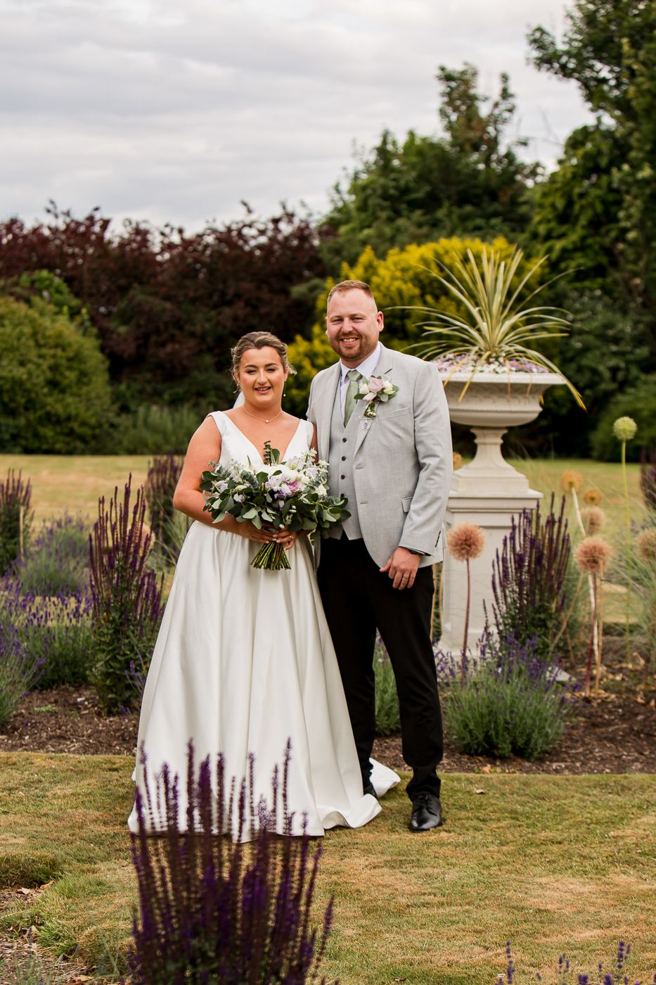 A couple celebrates their wedding day in a beautiful garden setting with lavender and ornamental features.