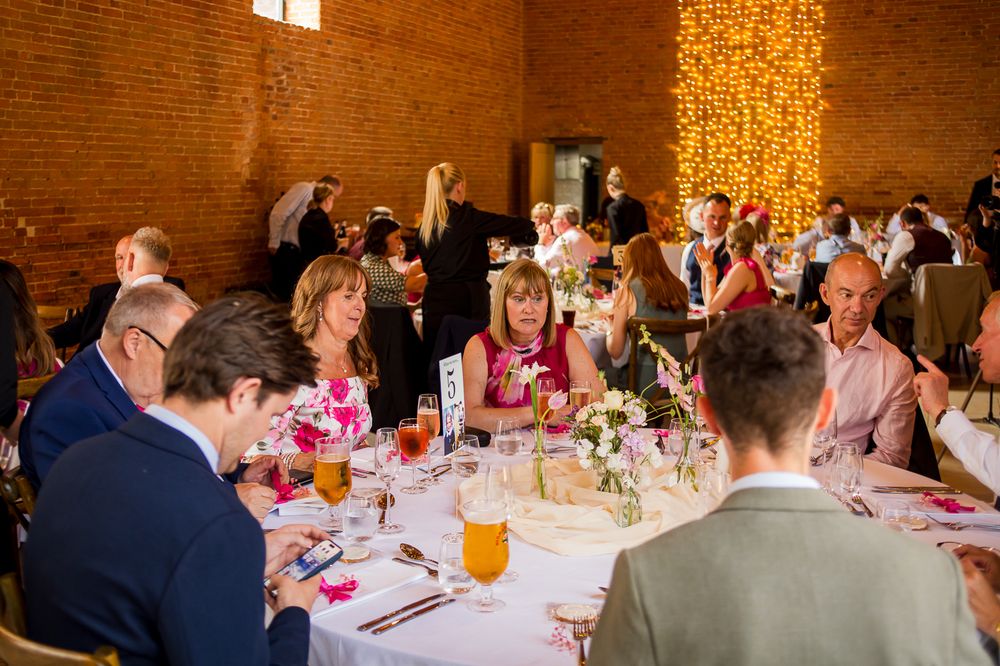 Wedding reception dining room with exposed brick walls and guests seated at round tables.