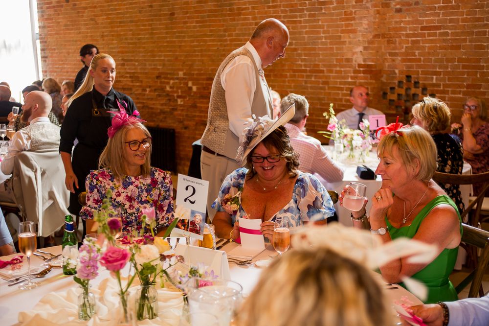 Wedding reception scene with guests dining at decorated round tables.