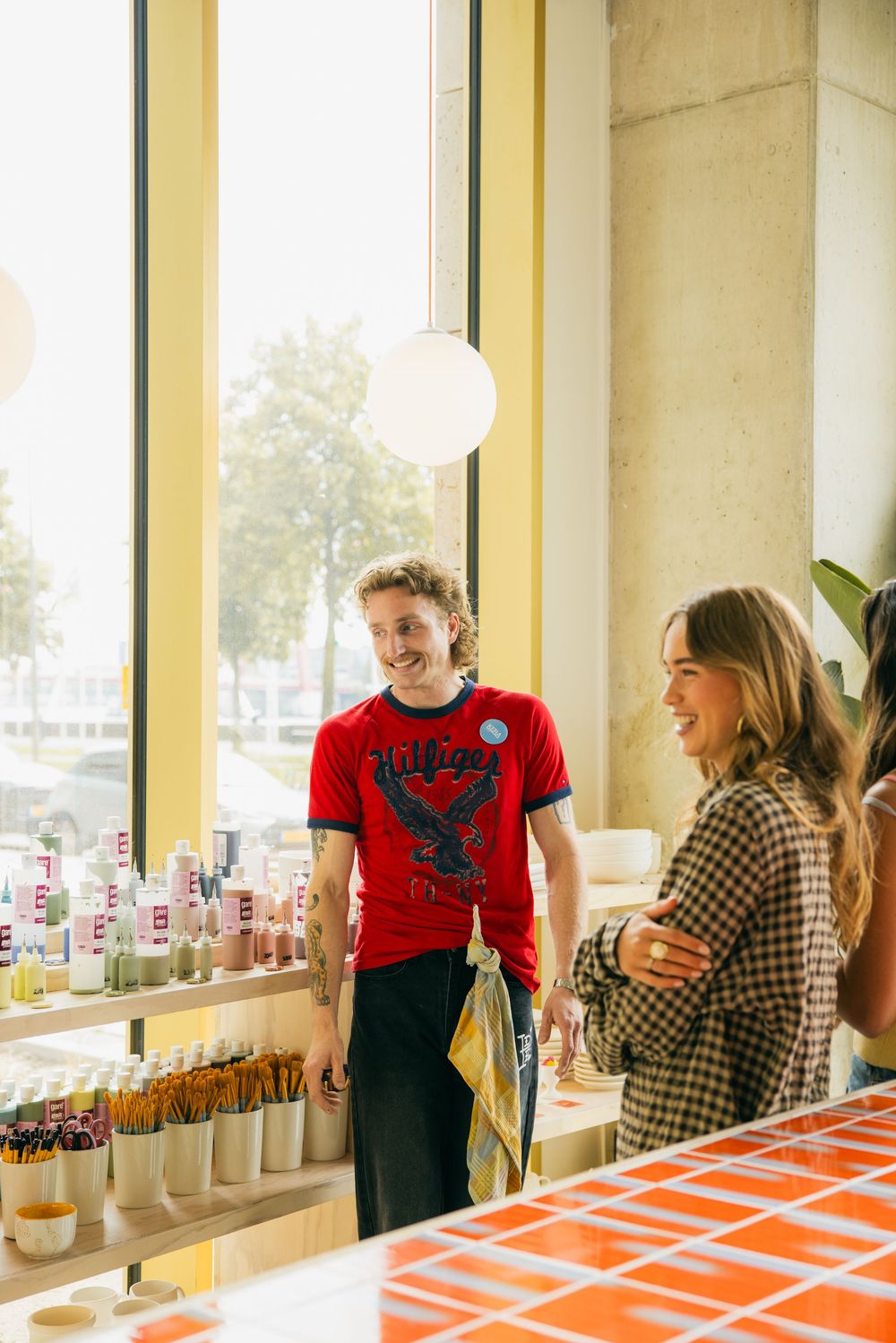 Two young people smile and chat at a colorful retail display near large windows in a bright modern store.