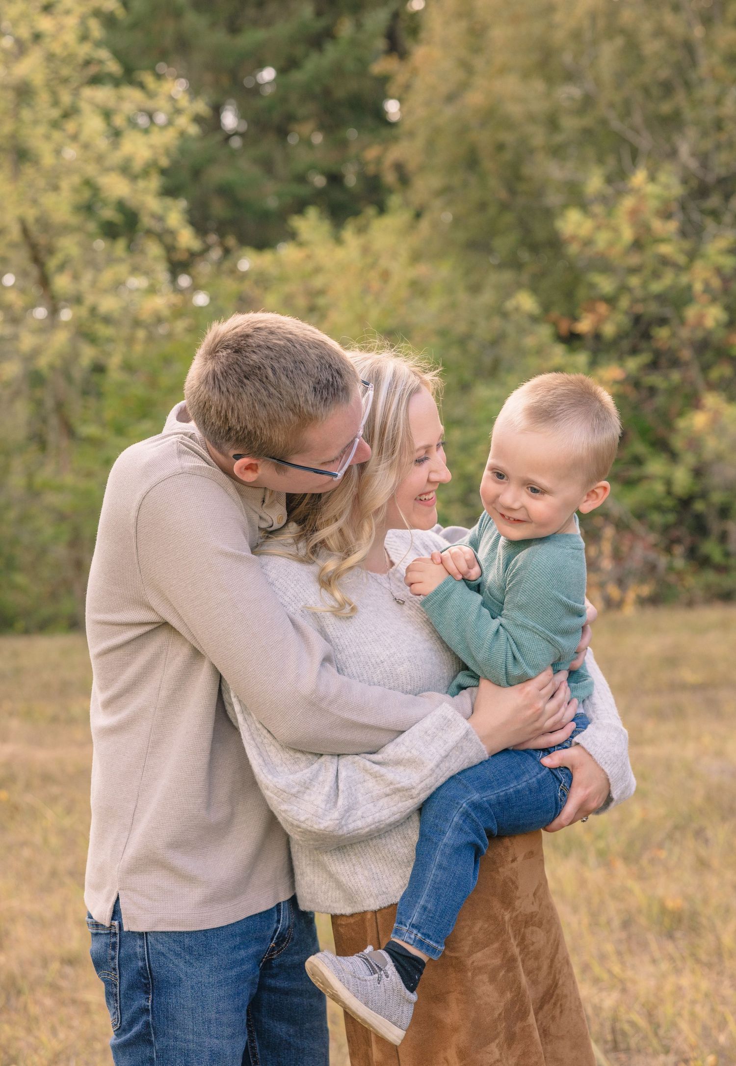 Family sharing playful moments together in autumn field setting.
