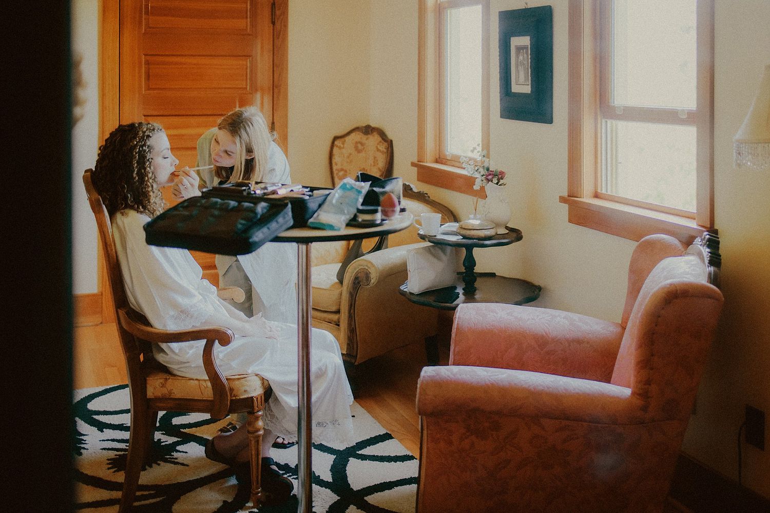 A cozy salon setup with vintage furniture and natural light streaming through windows.