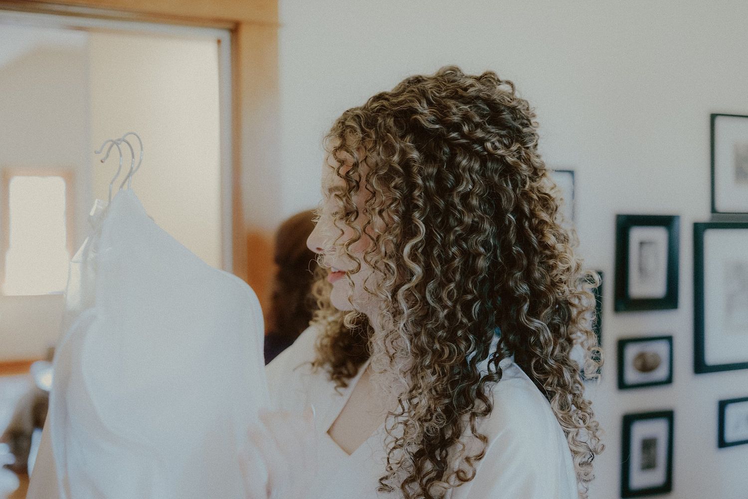Wedding makeup preparation scene with curly-haired person getting ready in a bright room.