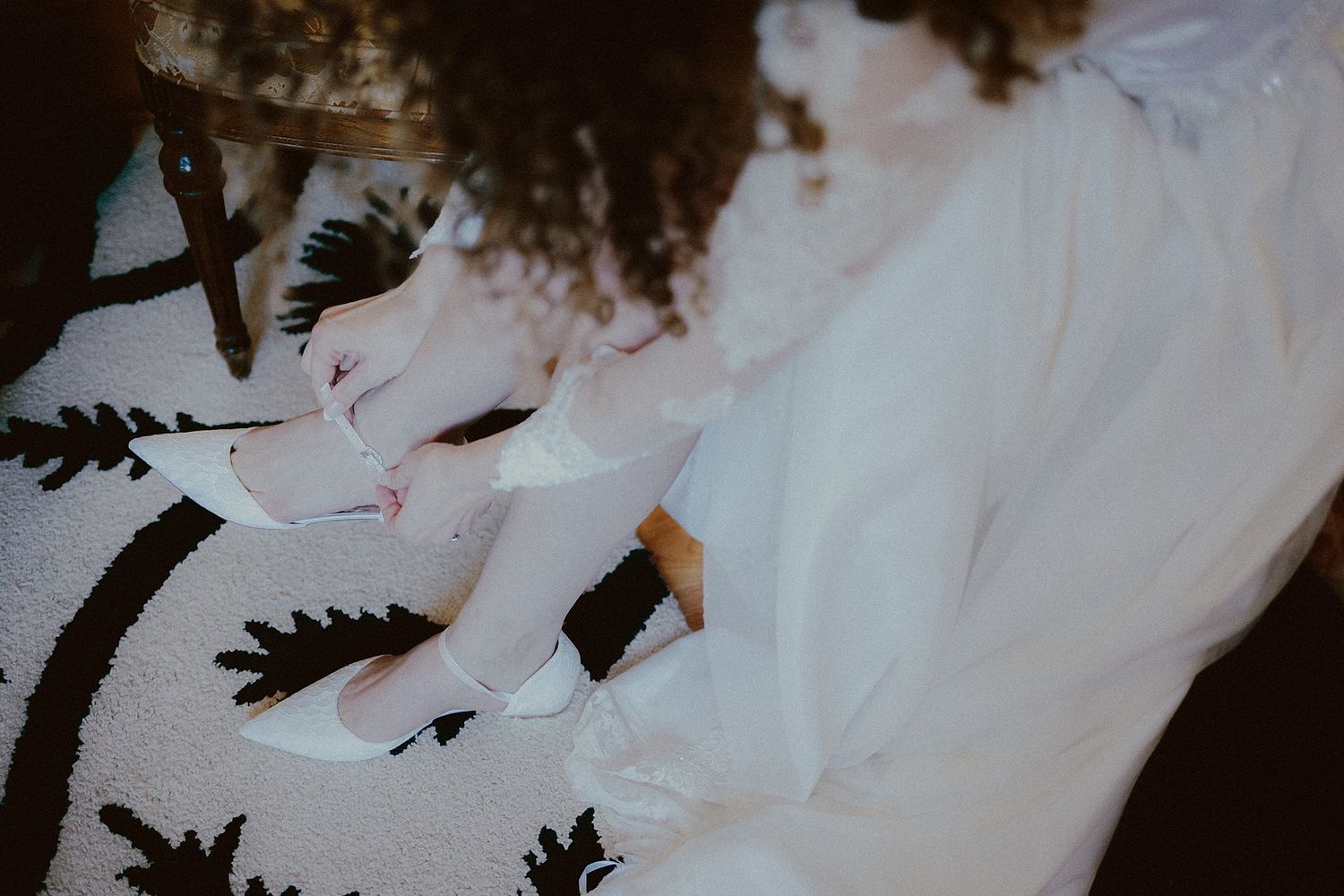 Close-up artistic shot of white wedding dress fabric against a dark patterned background.