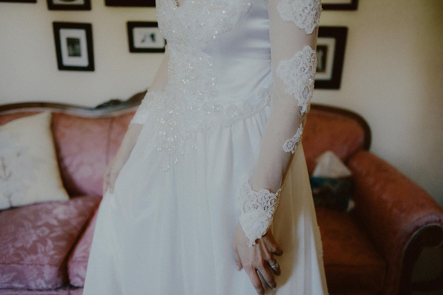 Detail shot of intricate lace sleeves and beading on a white wedding gown.