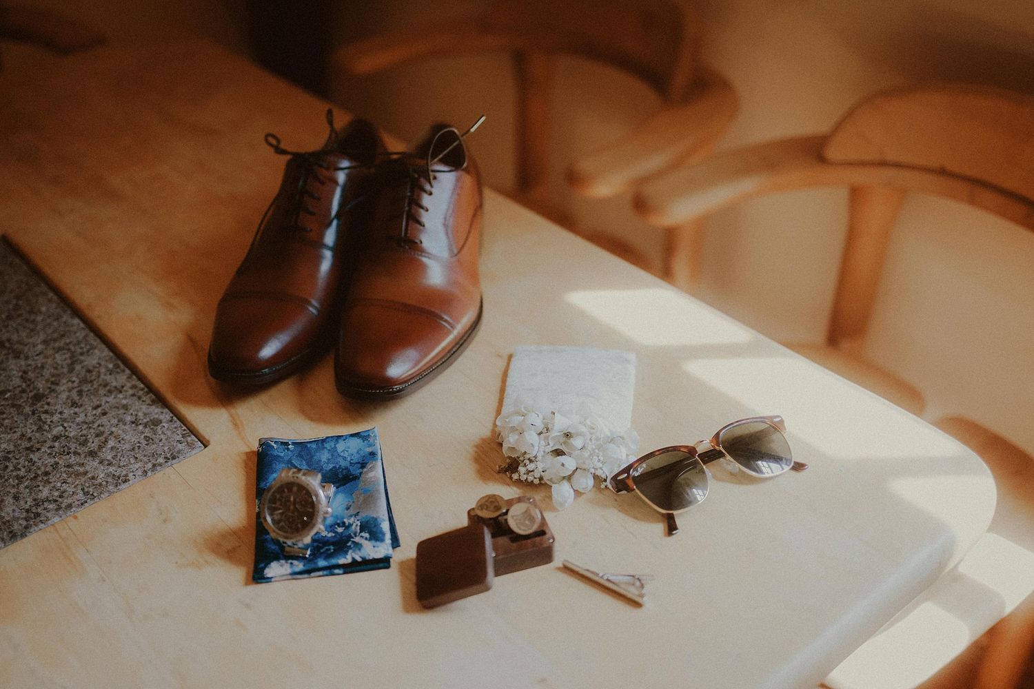 Brown leather dress shoes and boots arranged on a wooden floor during wedding preparations.