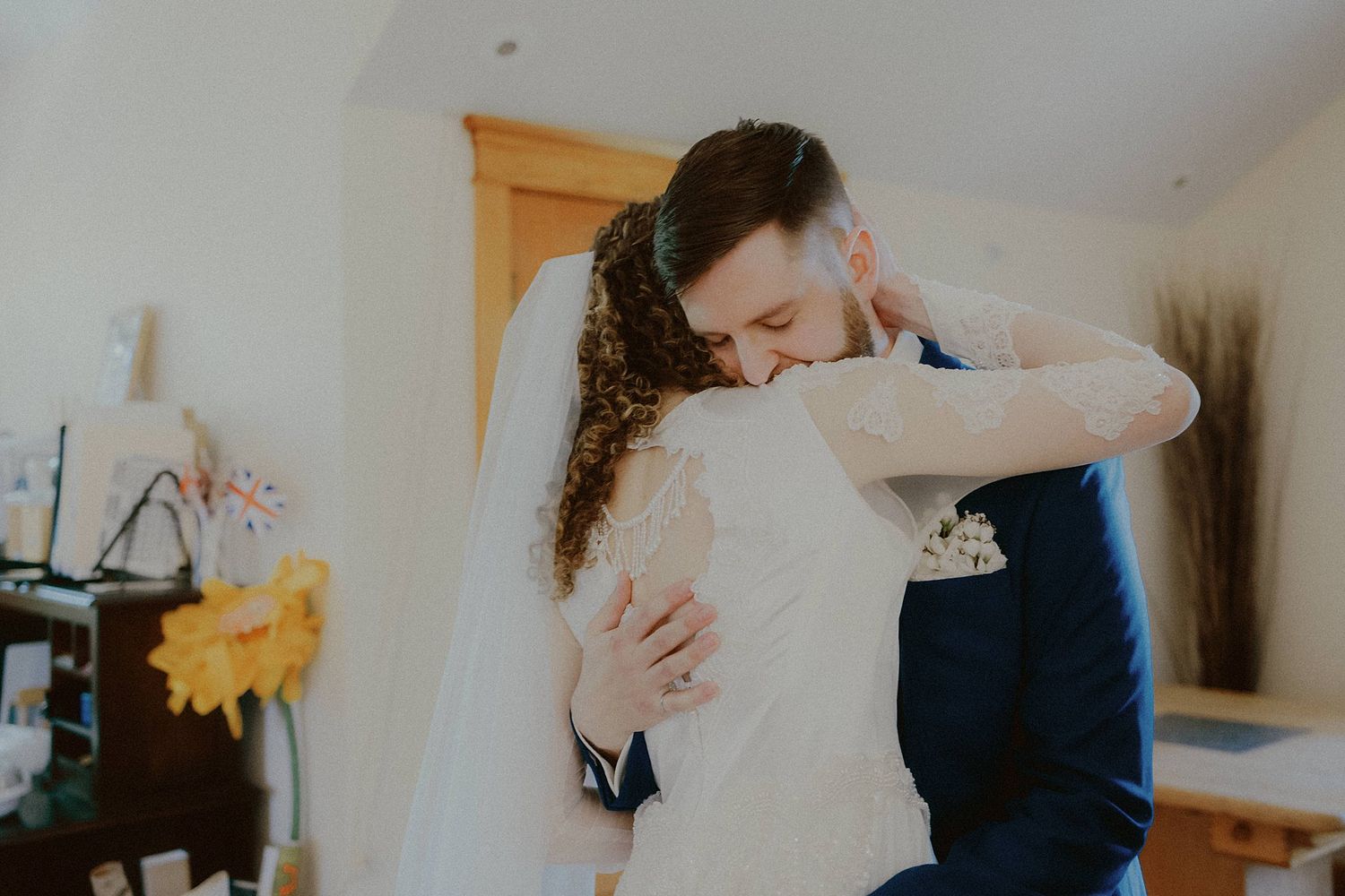 Intimate embrace between newlyweds during indoor wedding celebration.
