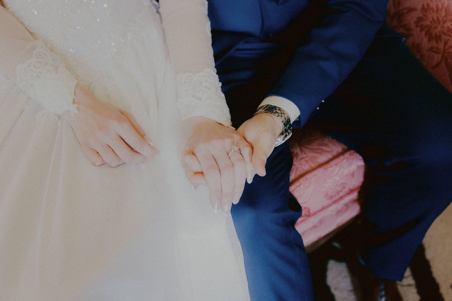 Close-up details of wedding preparations showing hands and formal attire.