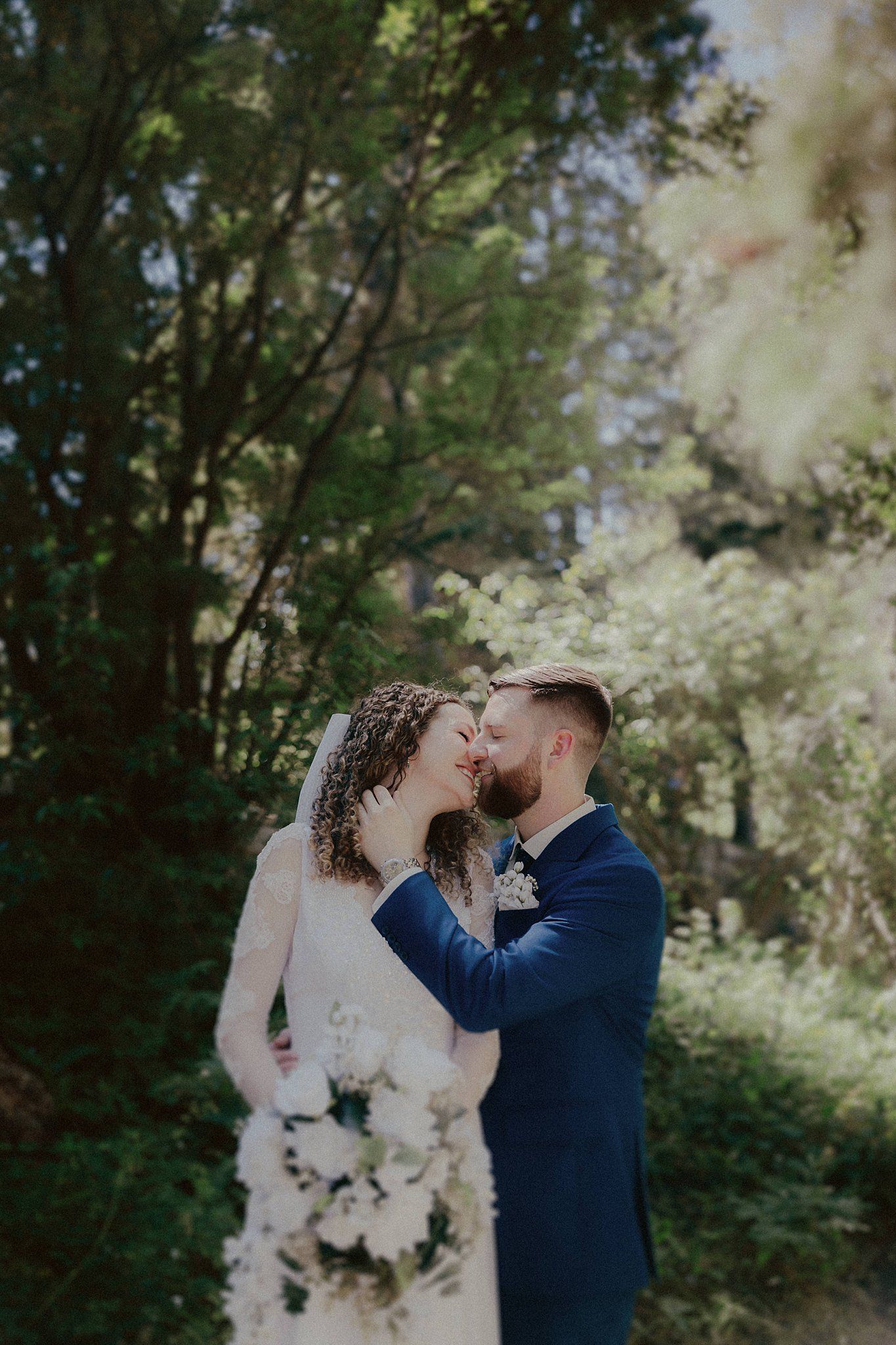 A romantic wedding moment captured in a lush forest setting.