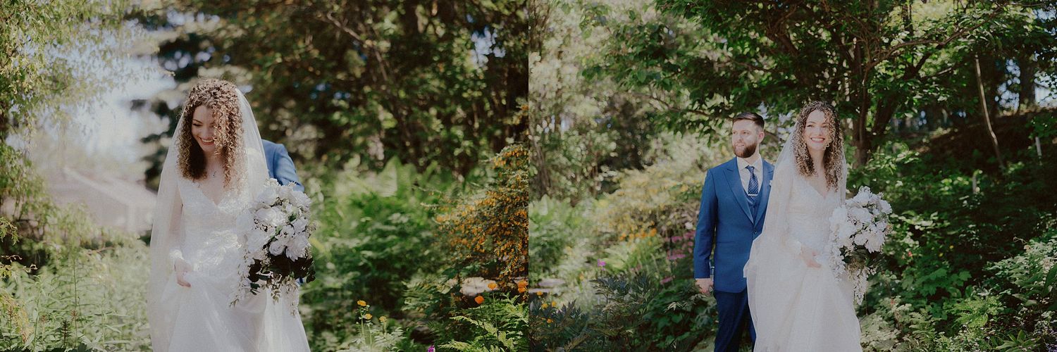 A wedding couple poses together in a lush outdoor garden setting surrounded by greenery.