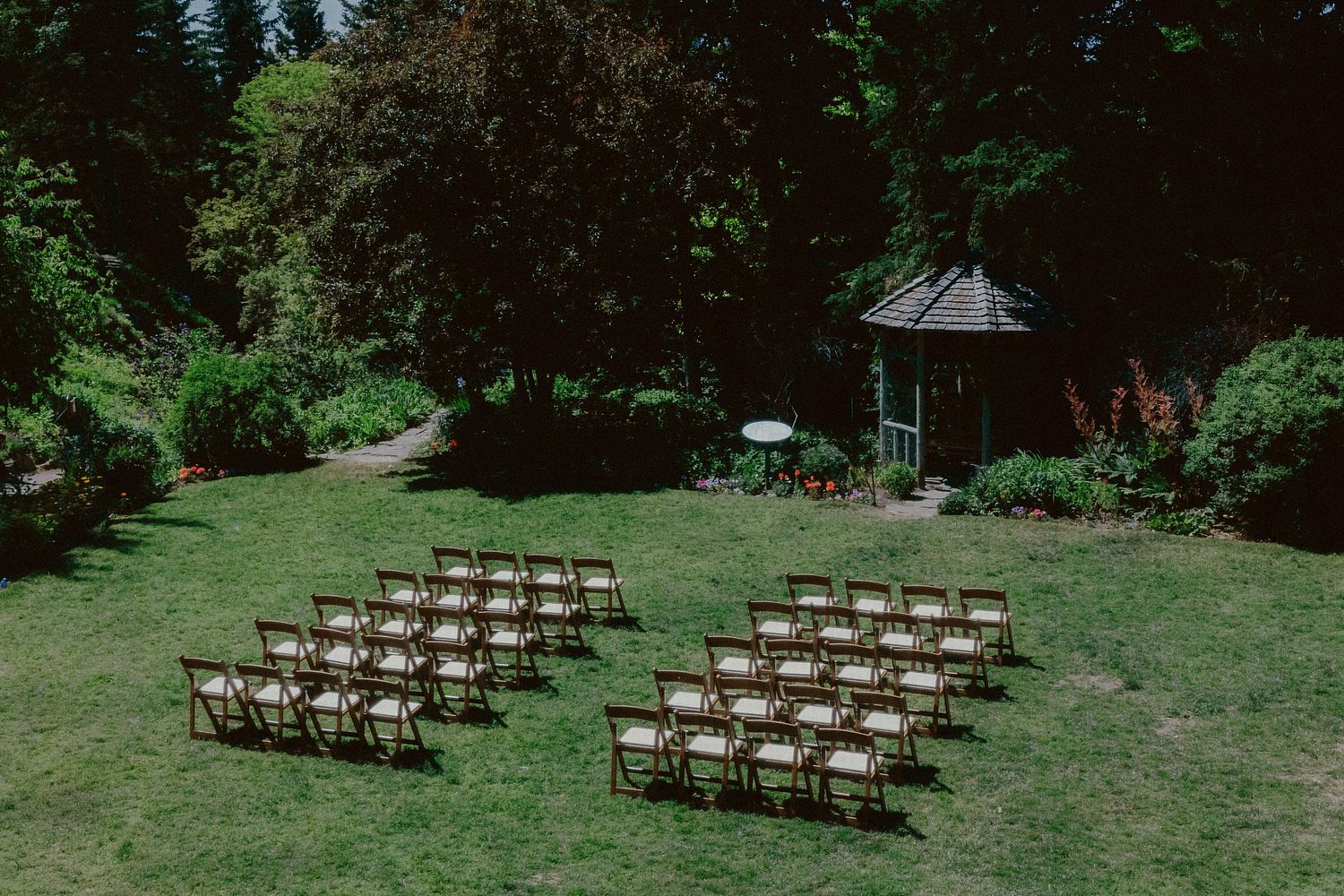 Wooden chairs set up in rows for an outdoor forest wedding ceremony.