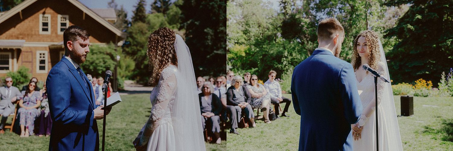 An outdoor wedding ceremony in progress with guests seated on wooden chairs among trees.