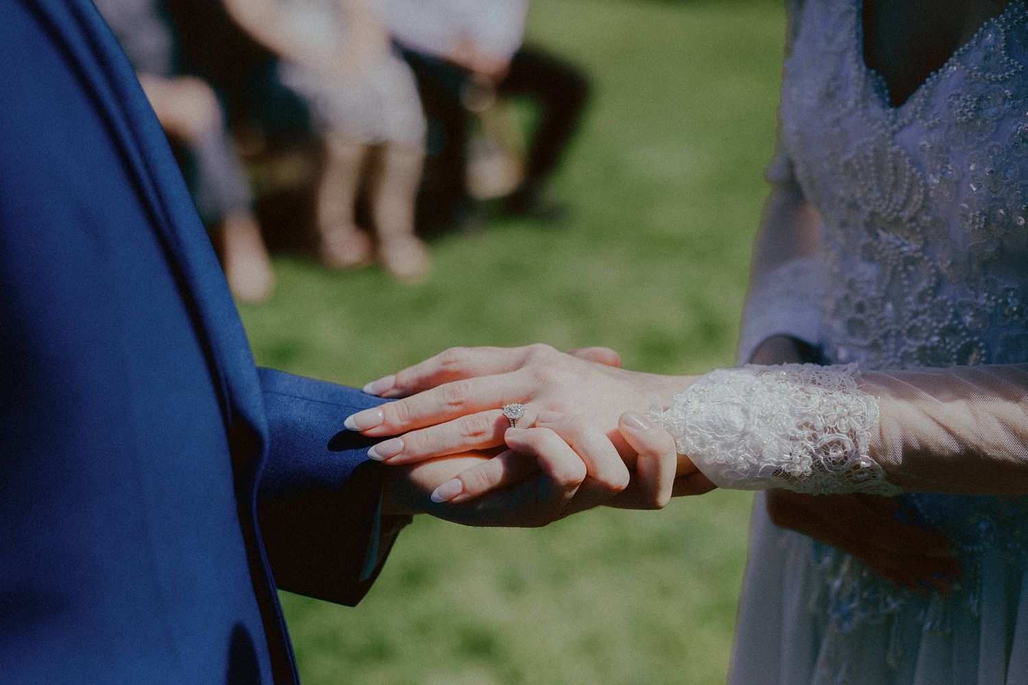 Close-up of hands exchanging rings during outdoor wedding ceremony.