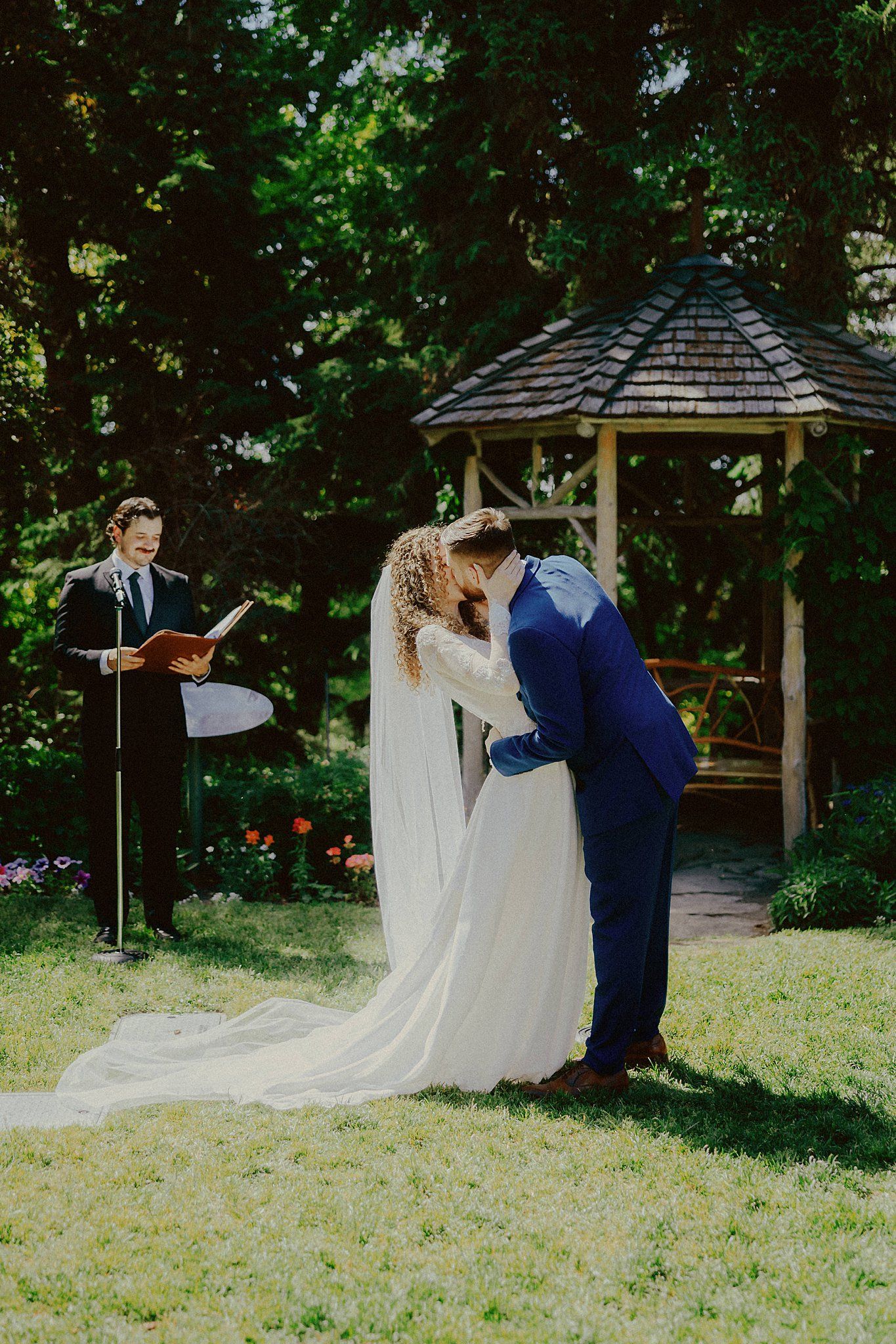 Couple sharing intimate moments under a garden gazebo during their wedding.
